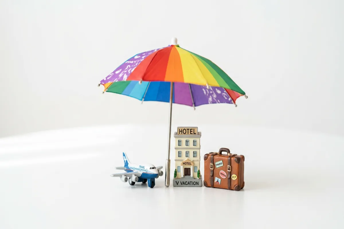 Travel insurance concept with umbrella protecting travel items